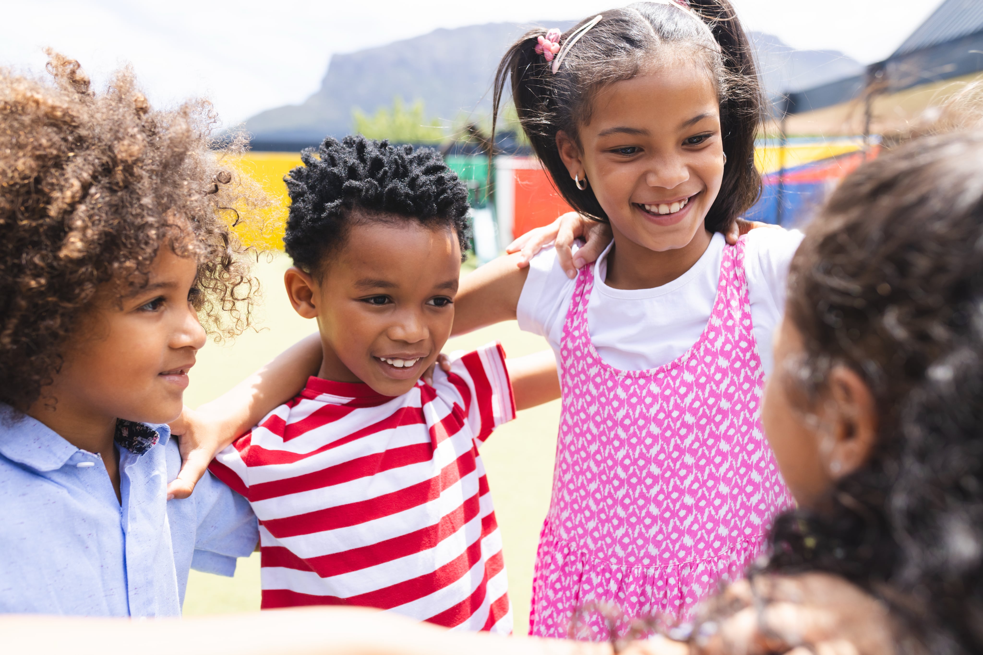 Diverse group of young children playing and laughing together outdoors
